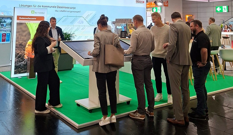 Viele Menschen stehen vor einem Terminal mit Touchscreen am Messestand von REMONDIS auf der KOMMUNALE 2025