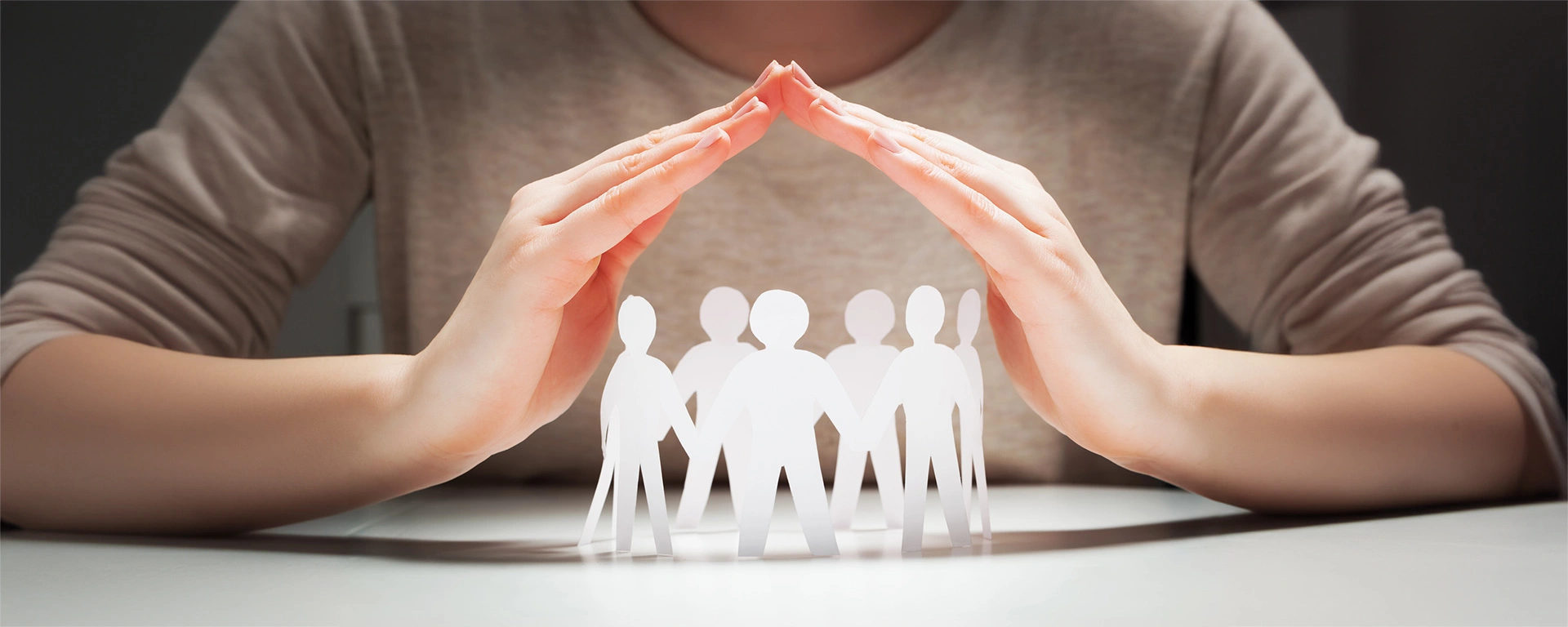 Ein Figurenkreis aus Papier unter schützenden Händen