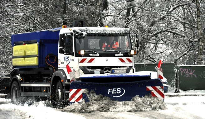 Großstreuerfahrzeug der FES im Winterdiensteinsatz auf verschneiter Straße.